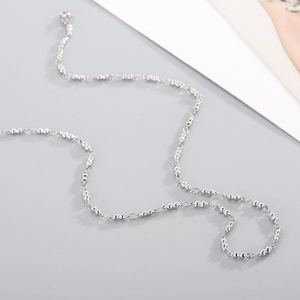 Minimalist silver beaded stainless steel chain necklace on a clean neutral background