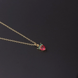 Detailed view of the strawberry pendant necklace with red and green zircon stones on gold chain