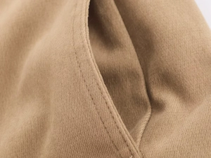 Gros plan sur les doubles coutures de la poche d'une veste kaki en tissu de coton