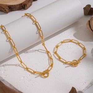 Minimalist gold paperclip chain necklace and bracelet set with OT buckle on white stone
