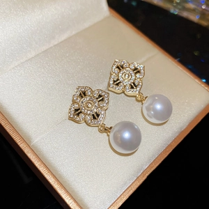 Macro detail of gold flower earrings with shimmering cubic zirconia and round white pearls