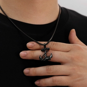 Close-up of a black titanium steel anchor pendant necklace worn by a male model