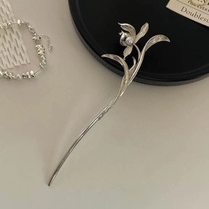 Detail of silver floral hair pin with white pearl and irregular metal chain bracelet
