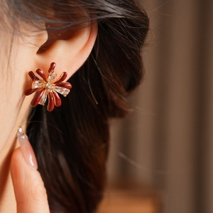 Close-up of elegant 18k gold plated red enamel flower earrings with zircon on model