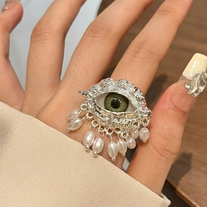 Vintage silver evil eye ring with green pupil and hanging pearls on a model hand