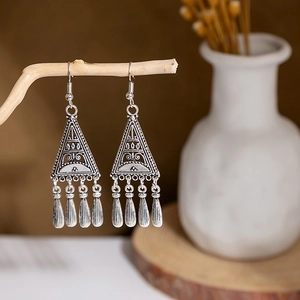 Macro detail of retro ethnic earrings with hollow triangles and metal tassels