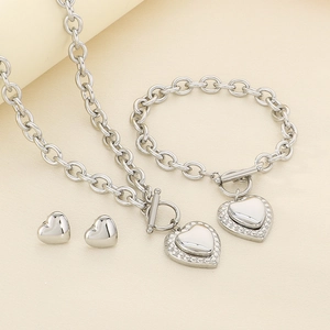 Detailed macro view of silver stainless steel jewelry set with heart charms and OT toggle clasp