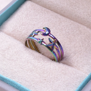 Close-up of rainbow-colored stainless steel ring with star and moon cutouts in jewelry box