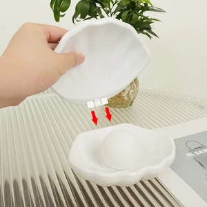 Detailed view of an open white shell-shaped night light and jewelry organizer on glass