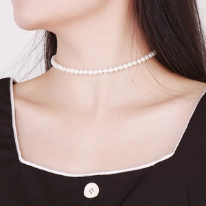Close-up of a white pearl choker necklace worn by a model for a minimalist style