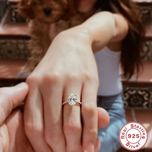 Close-up of an oval-cut diamond ring in 925 sterling silver on a hand in outdoor light