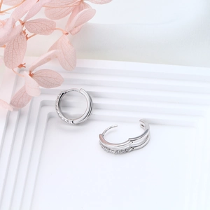 Detail view of silver hoop earrings with sparkling zircons on white display stand
