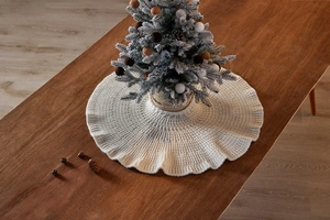 Detailed view of white knitted mini Christmas tree skirt with ruffled edges on wooden table