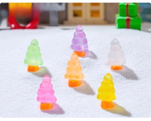 Close-up of colorful translucent resin Christmas trees on a fake snow background
