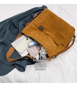 Détail d'un sac messager en velours côtelé marron montrant sa grande capacité et son étiquette