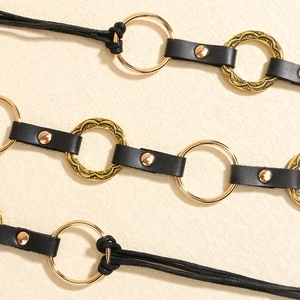 Detail of punk style waist belt featuring black leather strap and vintage gold metal rings