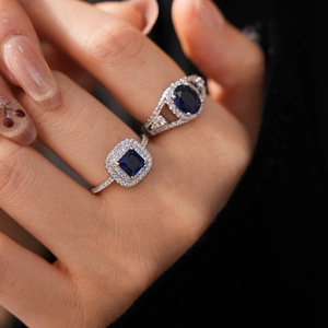 Detailed view of silver zircon rings with deep blue center stones on female fingers