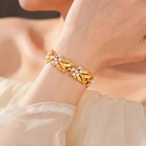 Close-up of vintage gold leaf bracelet with white pearls and sparkling zircon on wrist