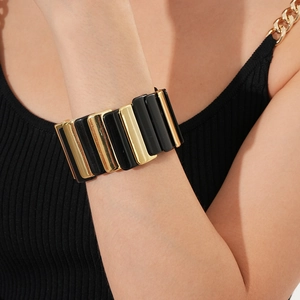 Detailed close-up of geometric black and gold link bracelet worn on a woman's wrist