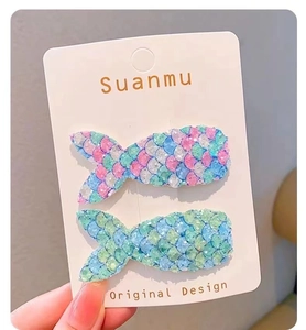 Détail de deux pinces à cheveux sirène avec paillettes colorées sur carte de support