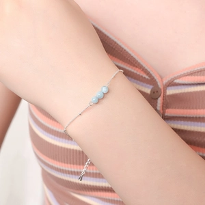 Detail of three light blue natural stone beads on a silver beaded chain for women