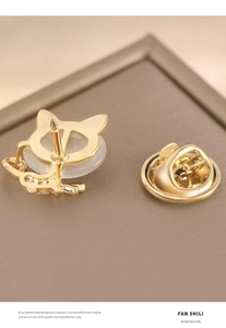 Macro view of a gold cat-shaped brooch featuring a polished metal finish and butterfly clasp