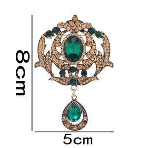 Detail of vintage palace style brooch with green gemstone and 8cm x 5cm dimensions