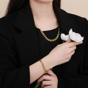 Nahaufnahme eines goldenen flachen Panzerketten-Sets aus Halskette und Armband auf Blazer