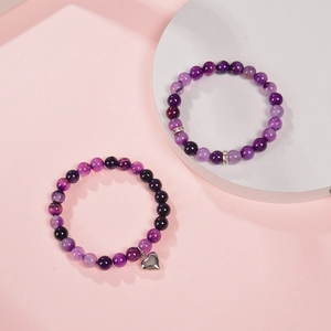 Pink zebra stone bead bracelet set with heart charm and sparkling accents on pink background