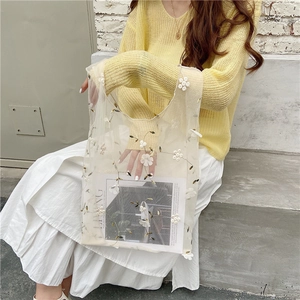 Detailed view of white mesh tote bag featuring 3D floral embroidery and lightweight fabric