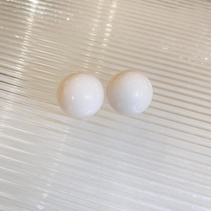 Macro view of polished round white pearl stud earrings on a textured background