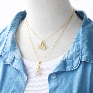 Close-up of golden Love letter pendant and curved necklace with sparkling zircons