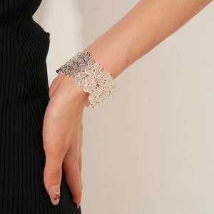 Detailed view of silver open cuff bracelet with hollow floral pattern on a woman's wrist