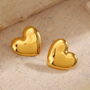 Boucles d'oreilles cœur en or poli sur un fond élégant en pierre beige naturelle