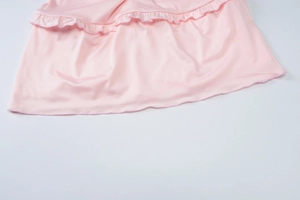 Close-up of pink fabric texture showing ruffle details and stitching on a summer outfit