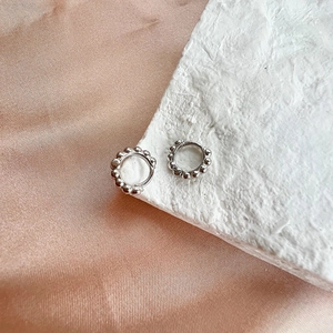 Detailed view of silver geometric hoop earrings with beads on pink satin and white display