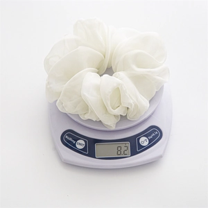 Detail view of a white chiffon scrunchie showing a lightweight 8.2g mass on a digital scale