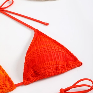 Dettaglio del top bikini rosso arancio con tessuto strutturato 3D e lacci