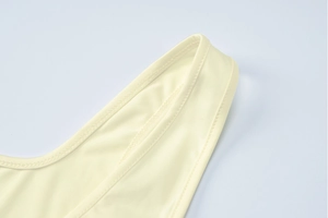 Close-up of light yellow knit fabric texture and high-quality seam detail on jumpsuit
