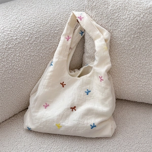 Close-up of colorful embroidered bows on off-white canvas tote bag with soft texture