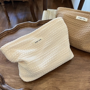 Detail of woven fabric pouches with 'simple wish' label in cream and brown on a wooden tray