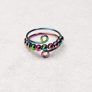 Detail view of rainbow beads sliding on a spiral titanium steel anxiety relief ring