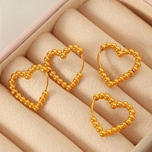 Elegant gold heart-shaped hoop earrings with beaded texture displayed in a jewelry box