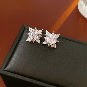 Close-up of silver snowflake earrings with sparkling zircons on a black leather jewelry box