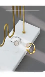 Macro shot of silver and gold branch texture rings with agate stones on marble stand