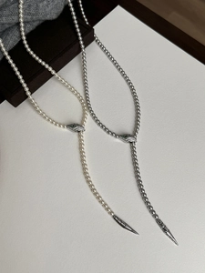 Macro detail of elegant pearl snake necklaces with emerald eyes and metallic pendants