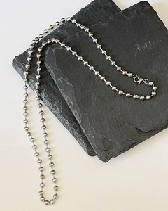 Detail of silver round bead chain necklace on slate stone with lobster claw clasp