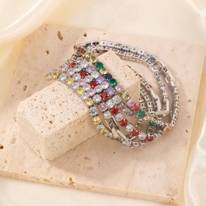 Micro-paved silver tennis bracelets with colorful gemstones on a textured stone base