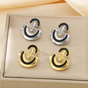 Detail of silver and gold D-shaped stainless steel earrings with black enamel inlay
