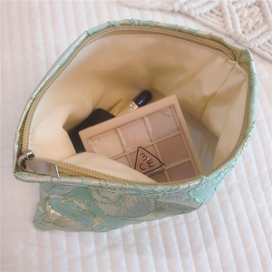 Detail of mint green floral jacquard makeup bag showing interior storage and silver zipper